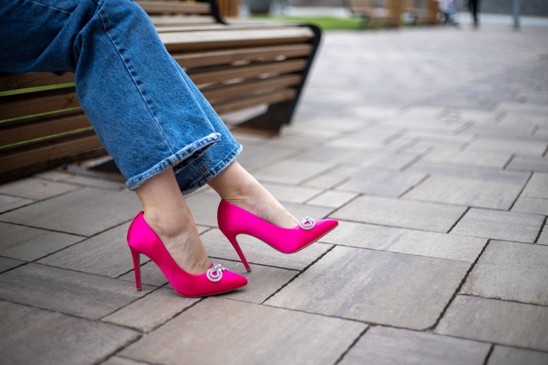 close-up of a woman's legs in jeans with bright fuchsia high-heeled shoes on the street